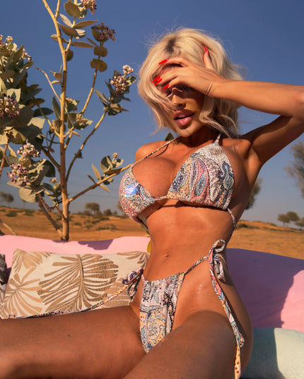 Model wearing the Arabesque Crystal Bikini embellished with sparkling crystals while posing in a desert setting, elegant luxury patterned swimwear by Donna Di Luxury.